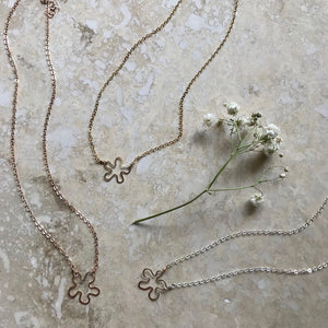 handcrafted tiny flower necklaces on marble background with baby's breath