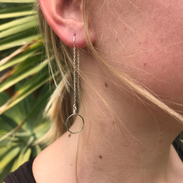 dainty, elegantly simple silver circle threader style earring on pretty blond gal in front of palm frond
