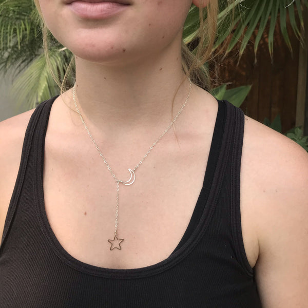 lariat style y-shaped crescent moon and open star necklace in silver & gold combo with dainty chain on model with black tank top