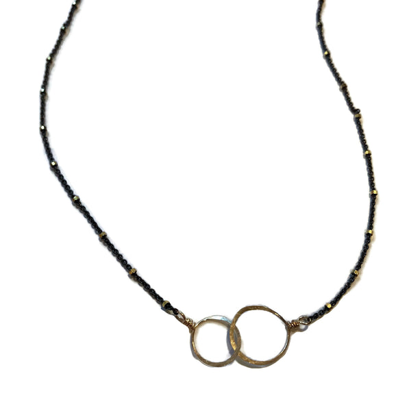 necklace with thin black chain with tiny gold beads featuring 2 hammered interlocking circles, beth jewelry